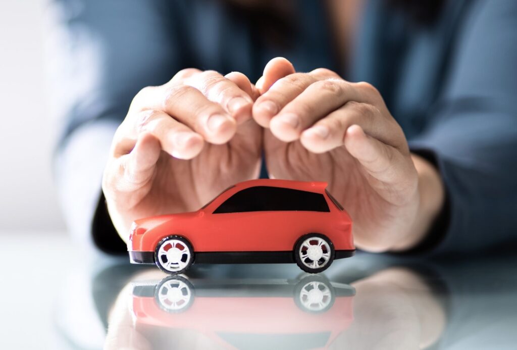 manos de una persona protegiendo un coche rojo