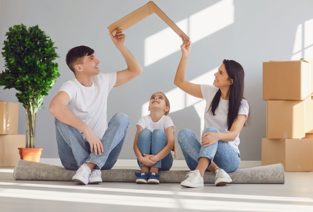 matrimonio joven sentados en el suelo en una casa en mudanzas con su niño pequeño sentado entre ellos